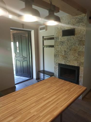 a room with a wooden table and a fireplace at Ranczo pod lasem in Lubenia