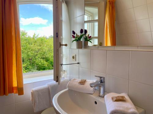 Un baño con lavabo, espejo y ventana. en Amaris-Sylt, en Munkmarsch