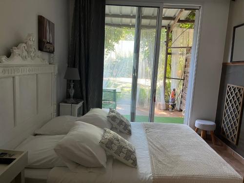 Un dormitorio con una cama con sábanas y almohadas blancas. en Chambre BELEM - MAS SAINT LOUIS, en Aigues-Mortes