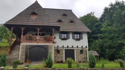 a house with a gambrel roof and a porch at River Song Inn in Vişeu de Jos