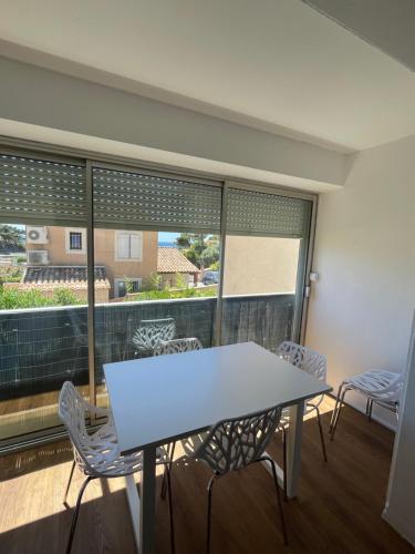 une table et des chaises dans une pièce avec une grande fenêtre dans l'établissement Appartement plage du cap Rousset carry le rouet 1 chambre 6 couchages, à Carry-le-Rouet
