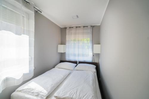 a bedroom with two beds and a window at Riviéra Apartmanház in Siófok
