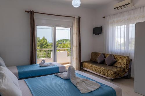 una camera da letto con due letti, un divano e una finestra di Vila Ylli Gjika a Ksamil