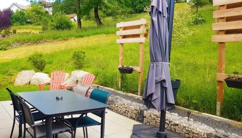 a table and chairs with an umbrella on a patio at "Le Cabanon cendré" petit chalet cosy au coeur de Gérardmer in Gérardmer