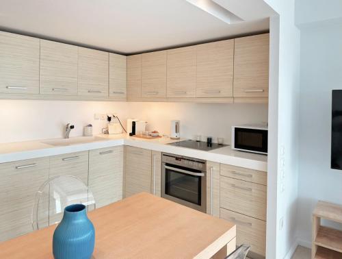 Dream View Vouliagmeni في أثينا: مطبخ بخزائن خشبية ومزهرية زرقاء على طاولة