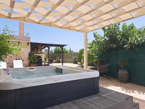 a hot tub in a backyard with a pergola at Chrisi`s house with jacuzzi in Moírai