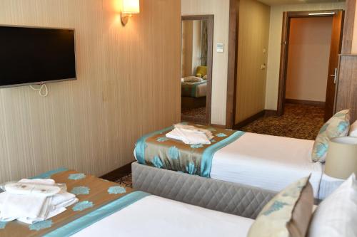 a hotel room with two beds and a flat screen tv at Royal Hotel Inegol in Inegol