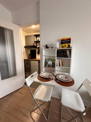 - une cuisine avec une table, des chaises blanches et une table dans l'établissement Studio cosy, calme et confort, à Villejuif
