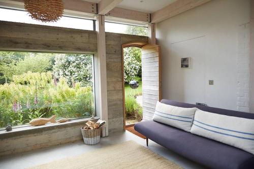 a living room with a blue couch and a large window at The Skyroom in Rendham
