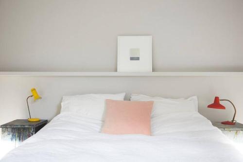 a white bed with a pink pillow on it at The Skyroom in Rendham