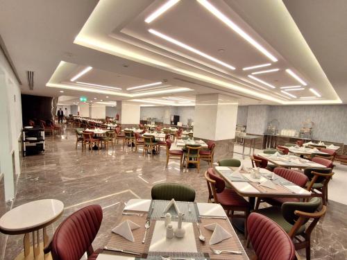 a restaurant with tables and chairs in a room at فندق مادن طيبة MADEN Taiba HOTEL in Al Madinah