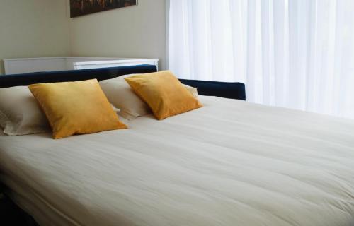 - un lit blanc avec 2 oreillers jaunes dans l'établissement Elegance w mobile Wi-Fi 7' to RER B Paris direct line Airports CDG and ORY, au Plessis-Robinson