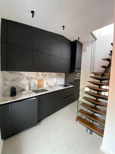 une cuisine avec des armoires noires et un escalier dans l'établissement T2 apartment historic center Ajaccio, à Ajaccio
