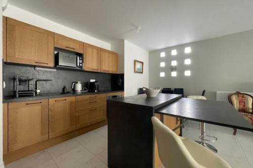 une cuisine avec des armoires en bois et un comptoir noir dans l'établissement New T4 near the Old Port of La Rochelle, à La Rochelle