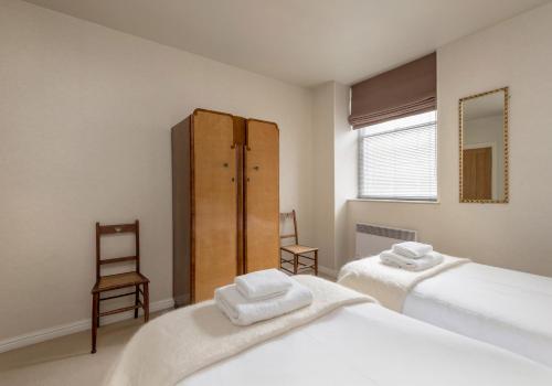 Un dormitorio con dos camas y un armario de madera. en Causewayside Apartment - The Edinburgh Address, en Edimburgo