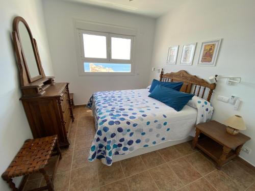 a bedroom with a bed with blue pillows and a window at Apartamento El Palmeral Aguadulce in Aguadulce