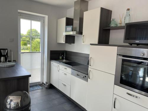 a kitchen with white cabinets and a stove top oven at Haus Am Dorfteich B eingefriedet in Fehmarn