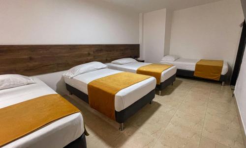 a room with three beds in a room at Hotel Boutique Estadio in Medellín