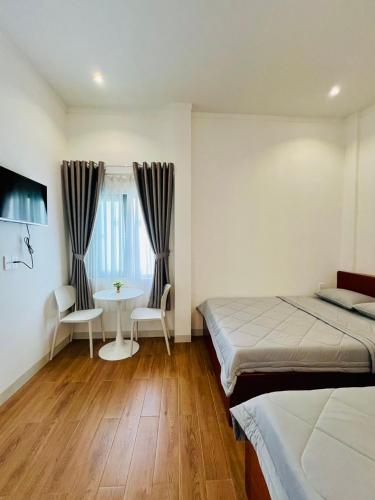 a bedroom with two beds and a table and a window at Triệu nguyễn in Buôn Kô Sir