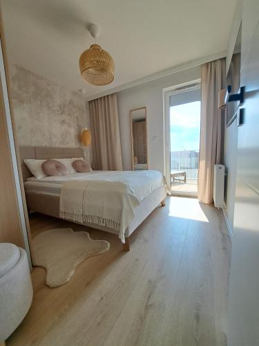a bedroom with a large bed and a large window at Apartament Słoneczny & SPA Plażowa A208 in Grzybowo