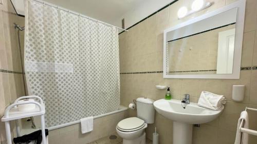 Un baño con inodoro, lavabo y espejo. en MarketHome Jardines del Mar Pool View, en Puerto de Santiago