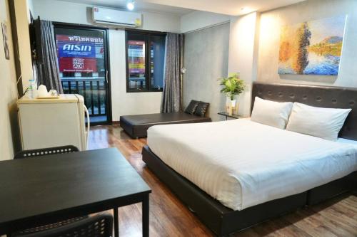 a hotel room with a bed and a table and a desk at Bkk39 Airport hotel in Ban Khlong Prawet
