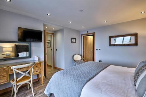 a bedroom with a bed and a desk and a television at Trefeddian Hotel in Aberdyfi