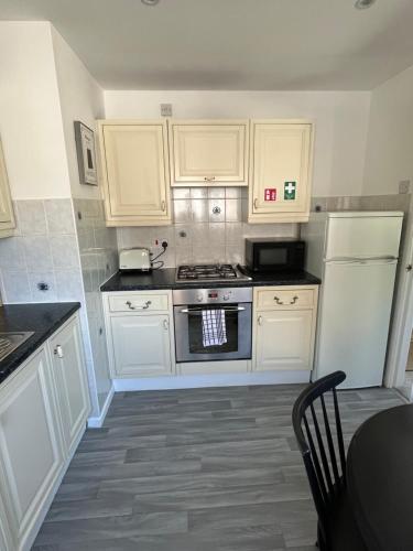 a kitchen with white cabinets and a stove at Cosy Bungalow in the Peak in Glossop