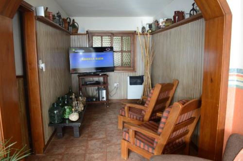 un soggiorno con 2 sedie e una TV a schermo piatto di Hostería El Bosque a Villa Gesell