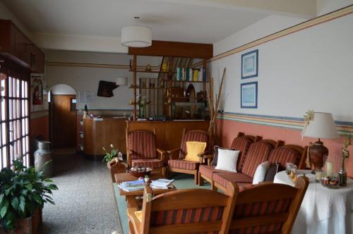un salón con un sofá y sillas y una mesa en la Hostería El Bosque de Villa Gesell