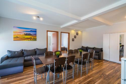 a living room with a couch and a table and chairs at Riviéra Apartmanház in Siófok
