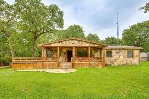 a log cabin with a fence and a grass yard at Deck and Fire Pit Unique Pottsboro Haven in Pottsboro