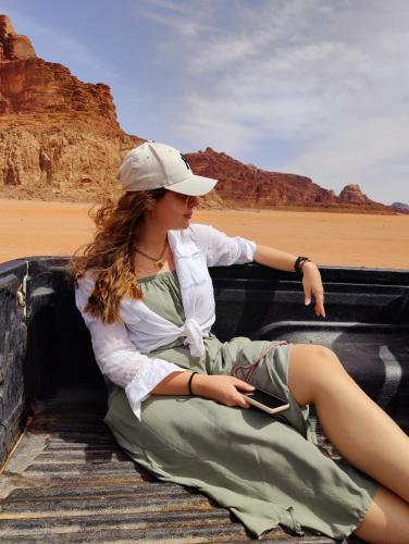 a woman sitting in a truck in the desert with a cell phone at Wadi Rum Desert Adventures in Wadi Rum