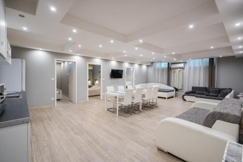 a living room with white furniture and a kitchen at Riviéra Apartmanház in Siófok