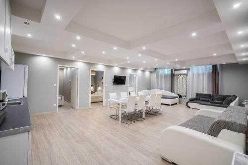 a living room with white furniture and a kitchen at Riviéra Apartmanház in Siófok