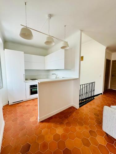 Il comprend une cuisine avec des placards blancs et du carrelage orange. dans l'établissement Appartement 2 chambres Le Willemi - St Tropez, à Saint-Tropez
