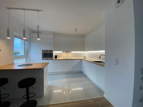 a white kitchen with white cabinets and a counter at Go2Nati apartament in Gdańsk