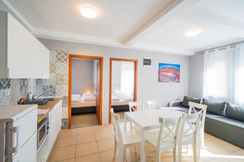 a kitchen and living room with a table and chairs at Riviéra Apartmanház in Siófok