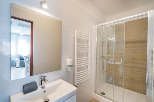 a white bathroom with a sink and a shower at Riviéra Apartmanház in Siófok
