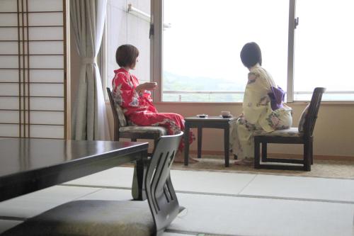 two women in kimonos sitting in chairs looking out the window at Hotel Kasuien in Ureshino