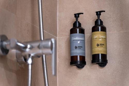 two bottles of shampoo are on the wall of a bathroom at Hotel SERHS Del Port in Barcelona