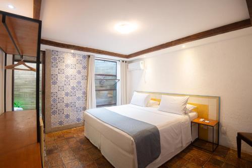 a bedroom with a white bed and a window at Pouso da Trilha Hospedagem in Lençóis