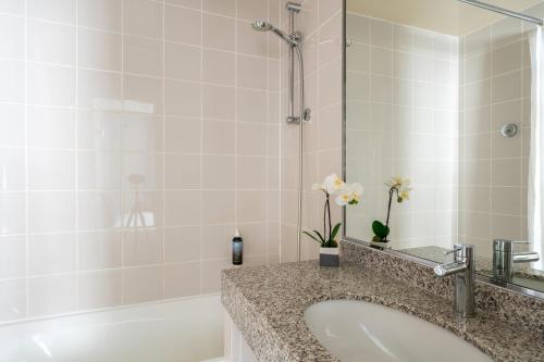 a bathroom with a sink and a tub with a mirror at Hotel Astoria - Astotel in Paris