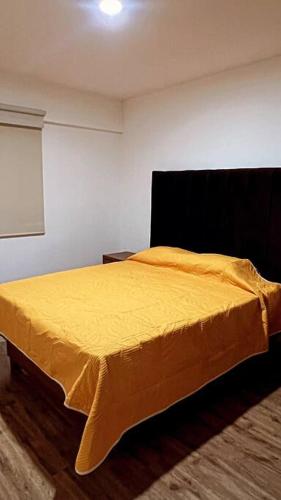 a bedroom with a bed with a yellow blanket at Departamento de Lujo in Jurica