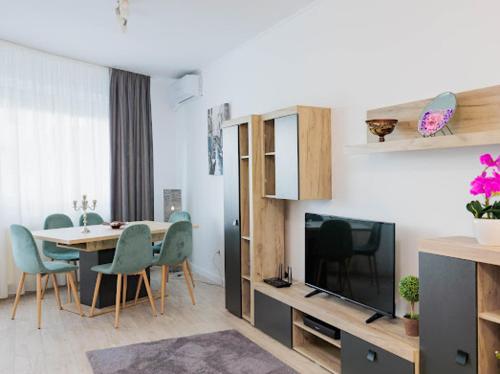 Una sala de estar con una mesa y sillas y un televisor. en Regia Apartament, en Oradea