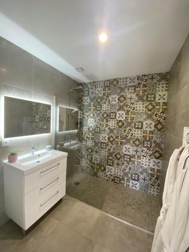 a bathroom with a white sink and a tile wall at Gîte de Chamelet - Nature et tranquillité in Chamelet