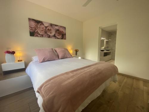a bedroom with a large white bed with pink pillows at Gîte de Chamelet - Nature et tranquillité in Chamelet