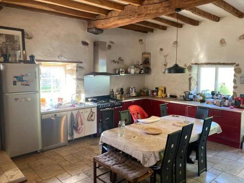 une cuisine avec une table et un réfrigérateur blanc dans l'établissement Maison au cœur du Pays-Basque, à Mendionde