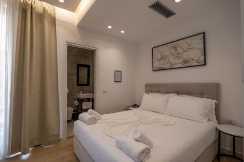 a bedroom with a white bed with towels on it at Art Hotel in Sarandë