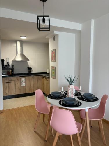 a dining room with a table and pink chairs at Apartamento a pie de playa La Pepa in Burela de Cabo